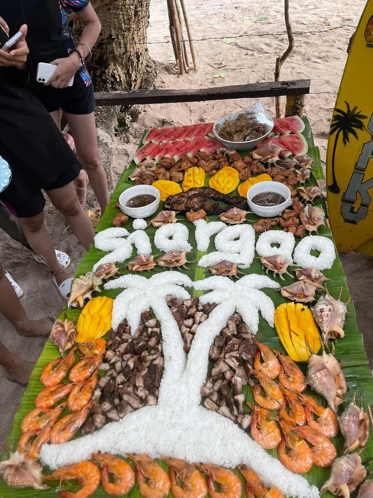 A beachside boodle fight feast on banana leaves with rice and seafood on Siargao