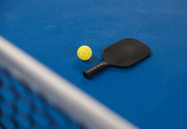 Pickleball paddle and ball on court