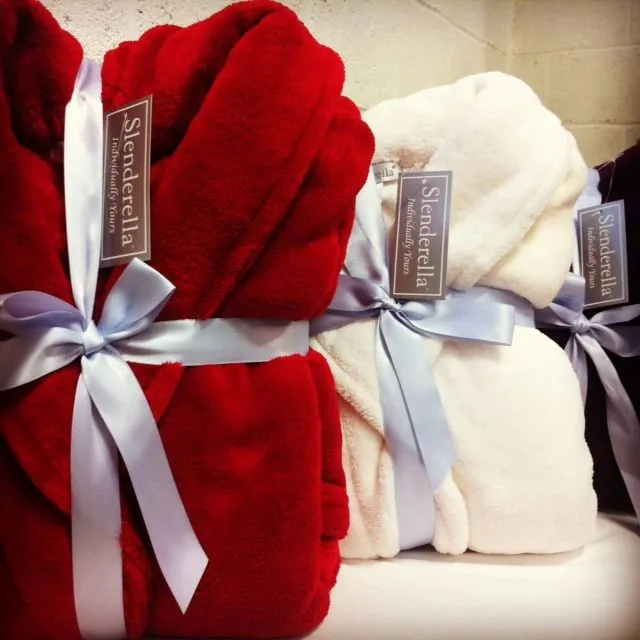 Custom terry-cloth bathrobe folded with embroidered property logo on tile floor for VIP gifting