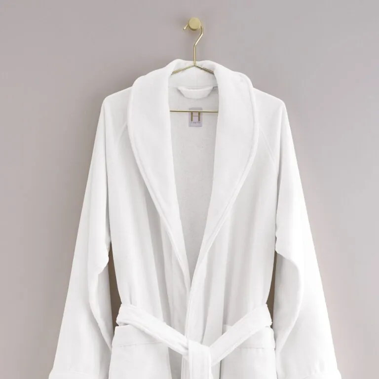 White shawl-collar terry-cloth bathrobe hanging on brass hook with woven brand label
