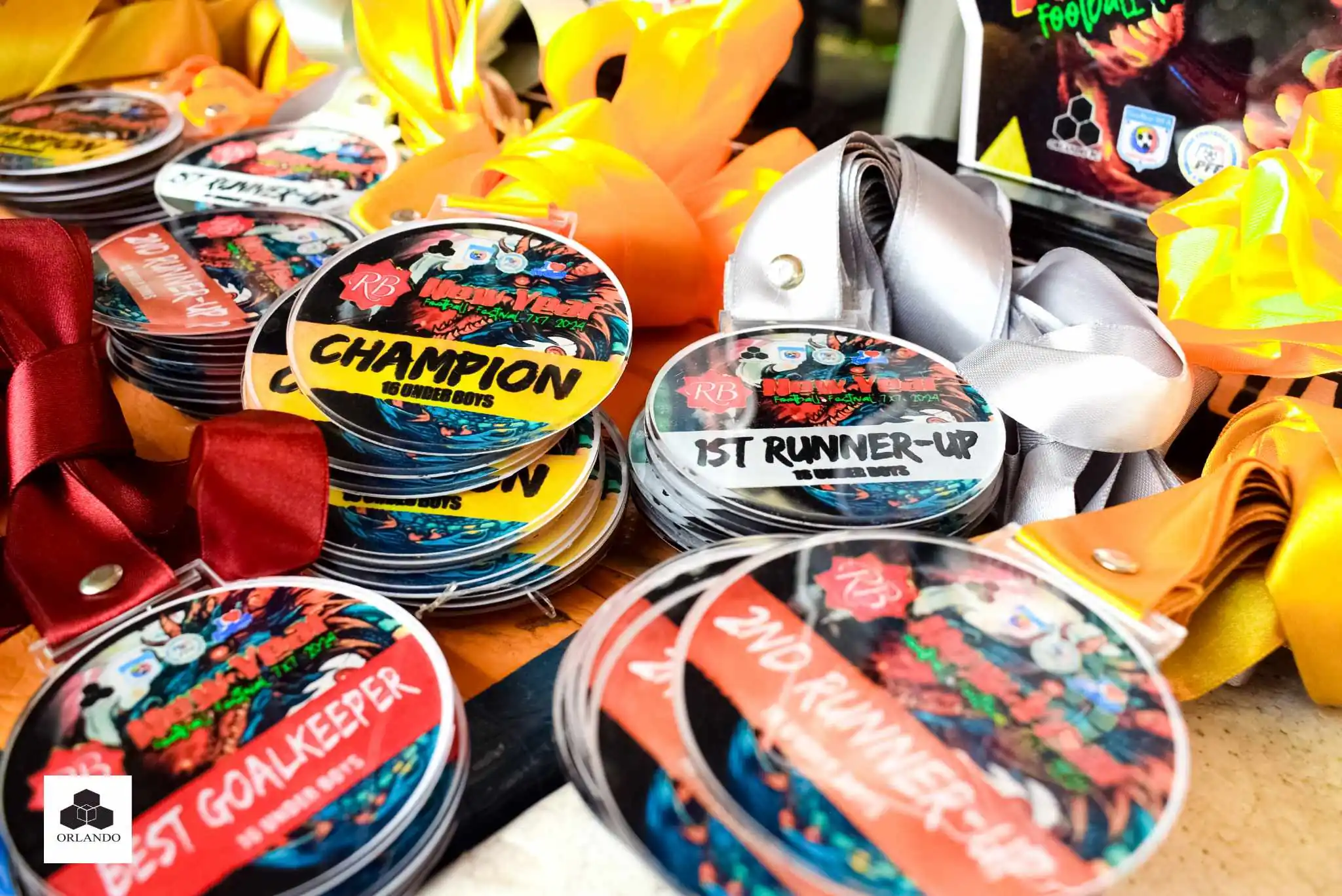 Stack of custom acrylic medals for a New Year Football Festival 2026 with Champion, 1st Runner-Up, Best Goalkeeper, and 2nd Runner-Up labels and multi-color ribbons