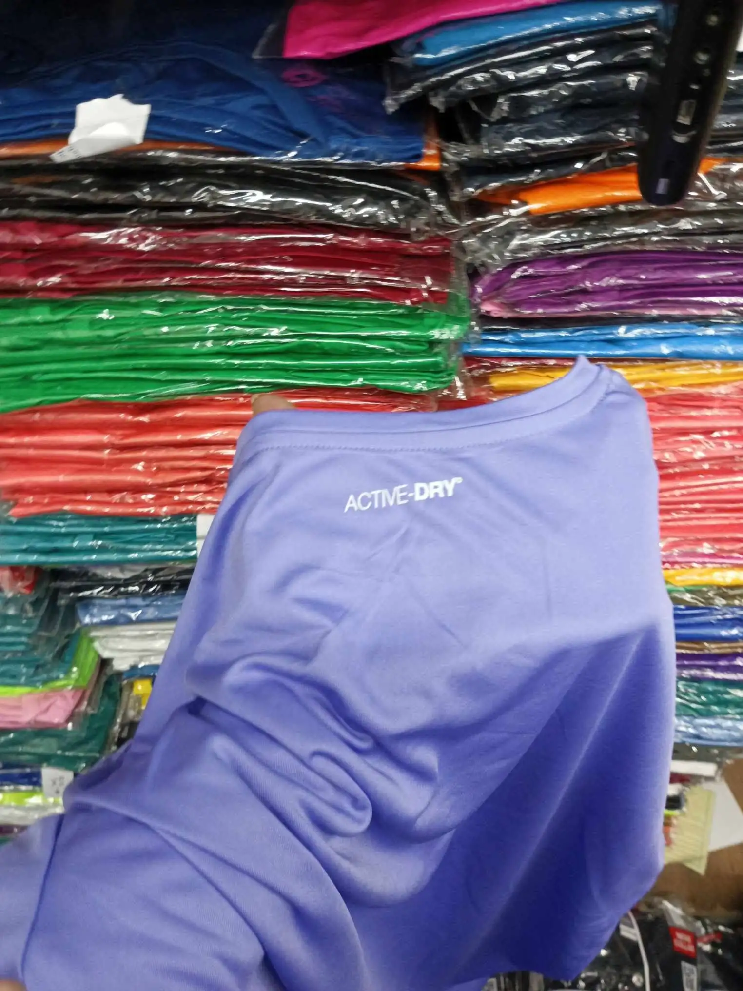 Wholesale t shirts wrapped in plastic stacked on bodega shelves