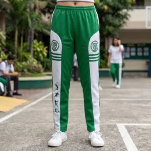 OLFU PE uniform jogging pants: green-and-white polyester tricot pants with Fatima University seal on side panels and sport-sprite silhouettes on the side stripe